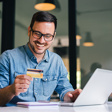 Man holding credit card smiling at laptop